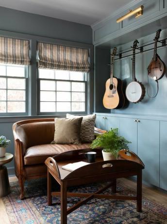 stue, blåmalte vegger, brun skinnsofa, brunt salongbord, musikkinstrumenter som henger på vegger, marokkansk teppe