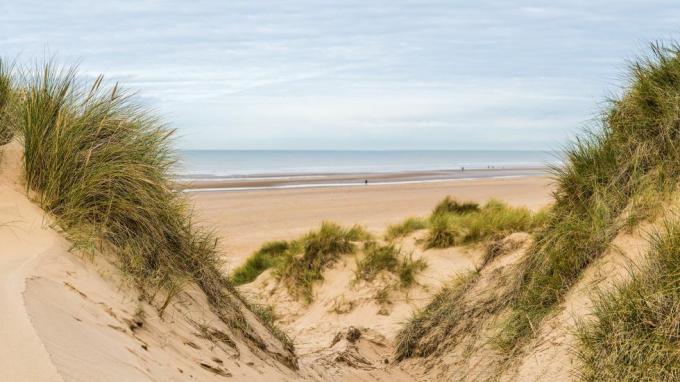 et panorama med flere bilder tatt mellom to topper på sanddynene og ser ned på folk som går langs Formby Beach nær Liverpool