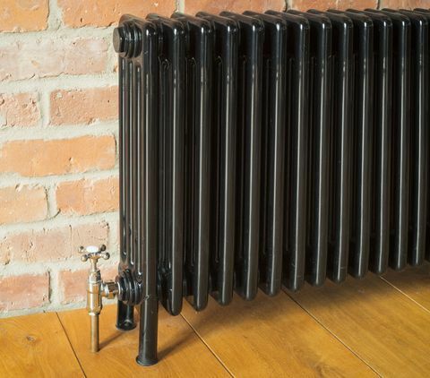 Svart radiator mot murvegg