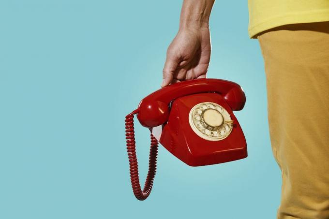 mann med en gammel rød telefon i hånden