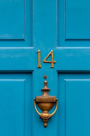 blå inngangsdør med dørhammer i messing