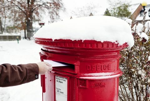 Mann poste brev i snødekket britisk postboks