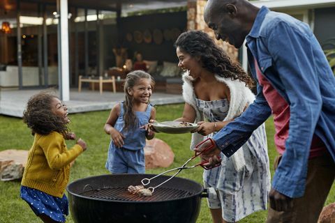 Familie matlaging på grillen i hagen deres