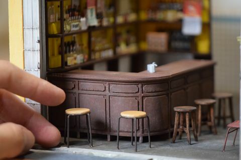 nærbilde av en miniatyrreplika av en bar, med barkrakker og en menneskelig hånd for skala