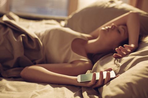 Nærbilde av en ung kvinne sovner ved siden av smarttelefon