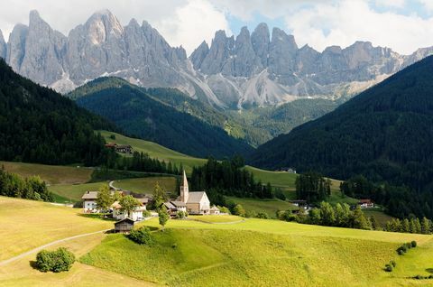 Sommerlandskap i idylliske Val di Funes med ulendte fjellkjeder i Odle (Geisler) i bakgrunn og en kirke i Village Santa Maddalena i den grønne gressrike dalen i Dolomiti, Syd-Tirol, Italia