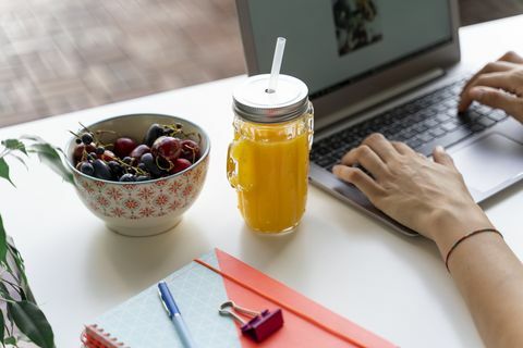 Nærbilde, av, kvinne, brukende laptop ved skrivebordet med appelsinjuice og frukt