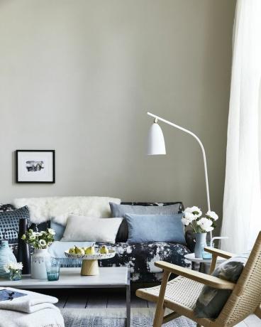 nøytral stue, stue med puter på den blåmønstrede sofaen, en hvit gulvlampe bøyd over sofaen teamdrips, flekker og sprutmønstre for et animpresjonistisk utseende som er moderne og avslappet