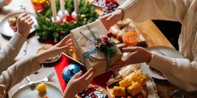 nærbilde toppvisning av ugjenkjennelig kjærlig forelder som gir festlig boks med julegave til glad sønn som sitter ved middagsbordet